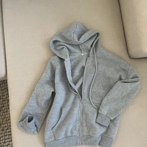 Grå hoodie - En nästan oanvänd hoodie/munkjacka med skönt tunt material som sitter perfekt på kroppen. Knappt använd och är därför i väldigt bra skick
