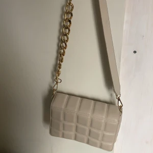 Väska 🤩 - Säljer en väska från H&M 🥰 Dens färg är krämvit med guldkedja, pris går att diskutera 💞