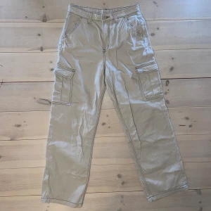 Beigea jeans - Ett par högmidjade beigea jeans med fickor på benen. Väldigt bra skick. Skriv för fler bilder.