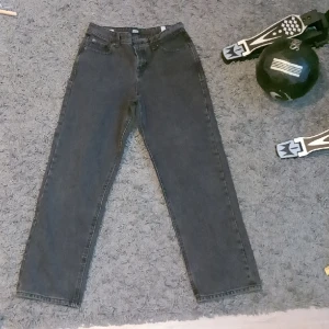 Jack and Jones Loose Jeans - Ett par snygga jeans från Jack and Jones i Mörkgrå/Svart färg. De sitter Straight/Loose. Jeansen har storleken 158.