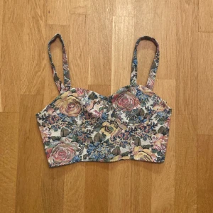 Blommig Topp/bralette i vintage stil, stl XS - Blommig topp/bralette i robust tyg. Står stl XS men skulle även kunna passa S. Enbart provad. Klicka gärna på köp nu och meddela för eventuella frågor. :)