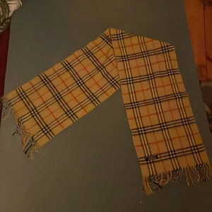 Burberry halsduk som ny - Burberry halsduk i bra skick 20 cm bred och 128cm lång passar för både kvinnor och män Ordinariepris: 3800
