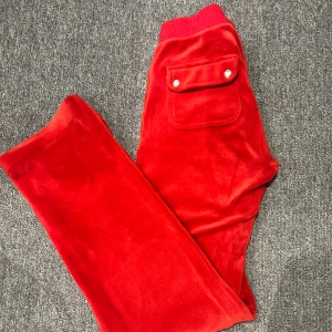 Röda Juicy byxor - Röda juicy byxor stl xs. Näst intill oanvända inga tydligare tecken på användning. Uppsydda ca 1-2 cm men det är ej synligt som du kan se på bilden. Jag skulle säga att dom passar alla mellan 155 och 165. (Nypris 1200)