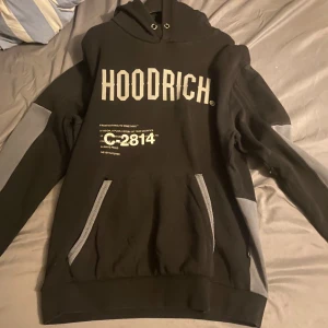 Svart och grå hoodrich hoodie  - Svart hoodrich med gråa färger fast den har ett litet hål vid stora fickan 