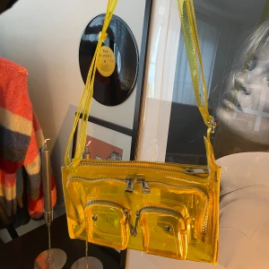 Nunoo väska gul - Otrolig väska från danska Nunoo jag älskat men inte får användning för längre. Gul färg och genomskinligt material. Justerbart band och flera fack💛Nypris 1100kr