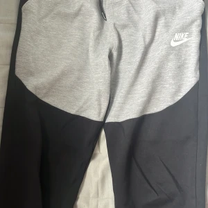 Nike tech byxor - Säljer ett par svart grå Nike tech byxor. Står inte storlek i byxorna men skulle säga xs/s. Unisex! Helt nya inte använda en endaste gång. Dm för mer info/bilder!