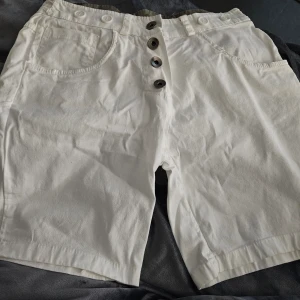 Shorts nyskick - Vita shorts med knappar framtill och fickor fram och bak. . 97% bomull. Made in italy. Använda 2 ggr så nyskick. Katt finns I hemmet