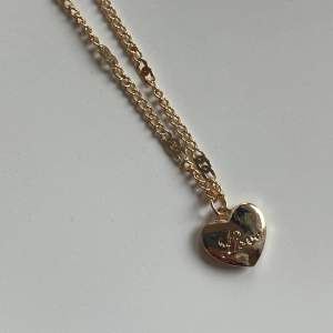 Halsband i rostfritt stål med guldplätering, ett hjärta där det står love, aldrig använt 