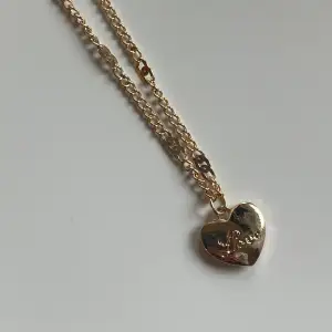 Halsband i rostfritt stål med guldplätering, ett hjärta där det står love, aldrig använt 