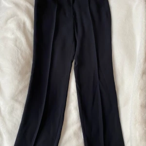 Nya svarta kostymbyxor från Ril’s modell Riia i strl 42. - Nya, aldrig använda.  Nypris: 2395kr  Mått Midjan: ca 43 cm Längd från grenen och ner: ca 84 cm  100% polyester   Kommer från ett djur och rökfritt hem.