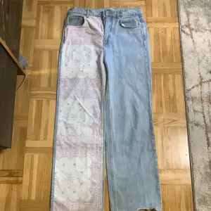 Blåa vida jeans med mönstrat tyg på ena sidan och backfickan. 