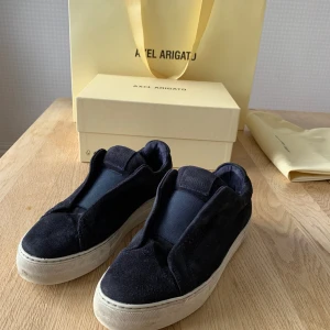 Säljer nu mina Axel arigato skor. Mockan är väldigt bra. Skon har två hål på ena sulan (se bild tre) hålen läcker inte in regn.  - Utom sprickan så är skon i väldigt bra skick.