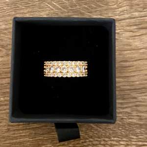 Guldpläterad ring i 18K med zirconia stenar. Faller inte i min smak av smycken därav säljer. Ringen har storlek 6 men är någorlunda större i storlek. Smyckesbox ingår