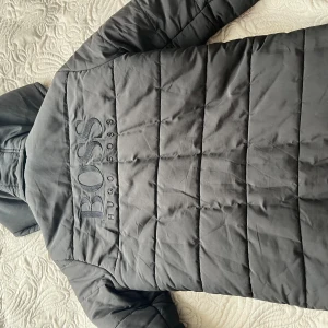 Hugo boss jacka - Helt ny och oanvänd Hugo boss jacka från Jhonnels i svart färg. Felfri och fint märke på ryggen. Köpt för 2000kr. Säljer för att jag vuxit ur den.