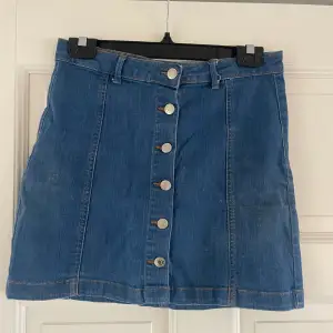 Söt jeans kjol från Gina Tricot med knappar fram till. Den är i en mer blåare färg jämfört med vanligt jeansmaterial.  Storlek 40