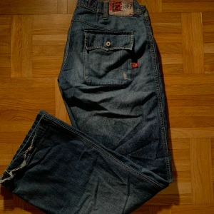 Lågmidjade blåa retro jeans  - Lågmidjade och baggy retro jeans med straight leg🙌 Köpta second hand men fortfarande i fint skick. Snygga fickor med knappar som detaljer. Fraktkostnaden är exluderar från priset. 