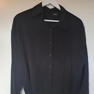 Asymmetrisk skjorta - En jättefin button-down skjorta med en asymmetrisk stil. Framsidan går till höften medan baksidan går ned över rumpan. Perfekt på kontor! 