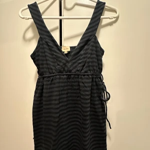 Svart och grå randig klänning - En svart och grå randig topp med knytning i midjan. jättefin med jeans eller shorts💘