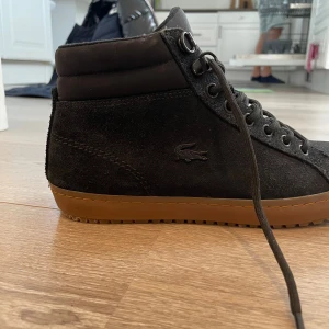 Lacoste skor - Nästan oanvända Lacoste skor som är vattentäta. Är svarta i mockaliknande material. Lätt fodrade. 