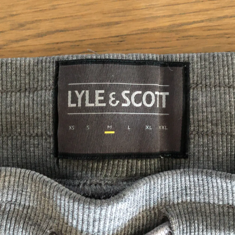 Ett par grå mjukisbyxor från Lyle & Scott med resårmidja och dragsko. Byxorna har två sidofickor och en broderad gul logotyp på vänster ben. Byxorna är i bra skick och lite använda! . Jeans & Byxor.