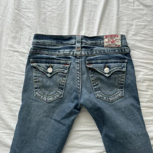 true religion low waisted bootcut jeans - w27, midjemåttet är 37cm och innerbennet är 81cm. low waisted bootcut true religion jeans. i bra skick förutom minimal slitage längst ner vid foten (dm om bild). pris kan diskuteras. 