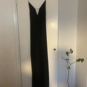Svart långklänning  - Svart långklänning med fina detaljer vid bysten, djup rygg och med slits på sidorna.
