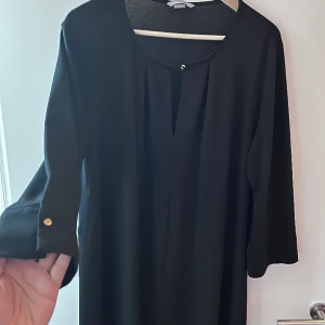 Svart klänning/tunnika med guldknappar  - I världen fin skick,lös på och kommer till knäna i längd.
