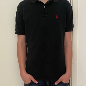 Ralph lauren pike - Nu säljer vi en svart Ralph lauren piké i ett väldigt bra skick. Modellen på bilden är 170 och den sitter väldigt bra på honom. 