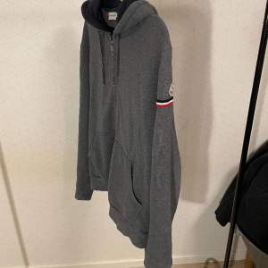 Säljer nu en fet moncler hoodie i storlek Xl. Tröjan sitter som en L, killen på bilden är 182 och bär L i vanliga fall. Tröjan är i okej skick men dock har badge börjat lossna lite, fråga för bild! Utöver de är tröjan i bra skick! Självklart Äkta!