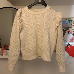 Stickad tröja med volang - Jättesöt vit stickad tröja med volang vid axlarna💗 Säljer på grund av att jag upplever den lite stickig, för kort i armarna för mig och att det inte är min stil längre. Typ aldrig använd. Köpt från sellpy för 120 kr 💕