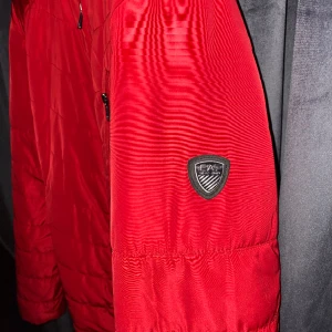 EA7 jacka  - En mycket fin och unik EA7 jacka! Den är i perfekt skick, absolut inget fel på den, knappt använd. Köptes för  1900kr från Johnells!   Bilden blir lite suddig för någon anledning. Meddela oss för en bättre bild! 