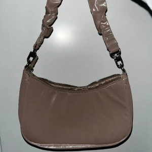 Vöska - Vin blank väska med ett lite unikt handtag. Inte använd mycket, så fint skick.