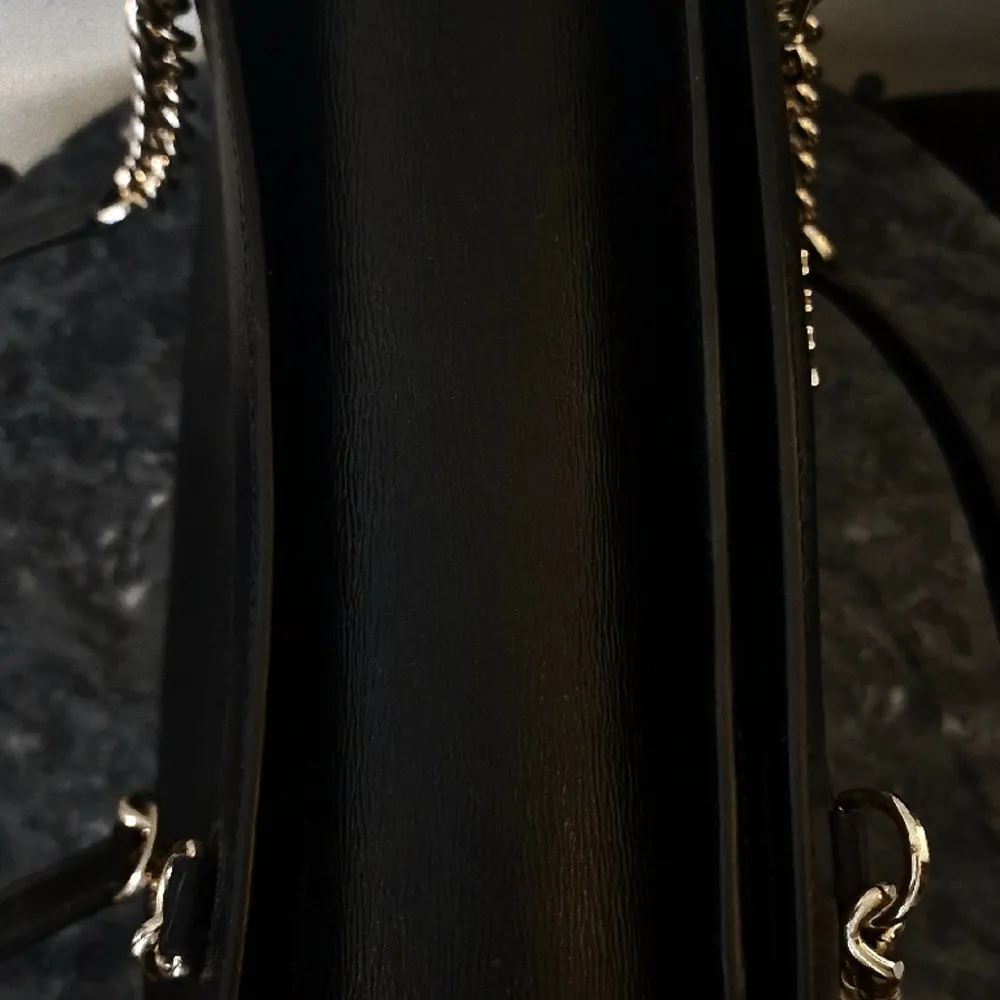 Stilren väska i svart skinn från DKNY. Den har dubbla huvudfack och ett mellanfack med dragkedja samt några mindre fack. Perfekt att ha till vardags med plats för allt man behöver.  Väskan har använts vid några tillfällen och har inga slitage.. Väskor.