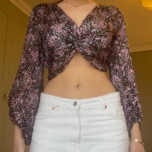 Kort mönstrad zara blus - Blusen har som en knytning mitt på och långa böljande ärmar. Den är lite lätt glittrig. Gott skick.