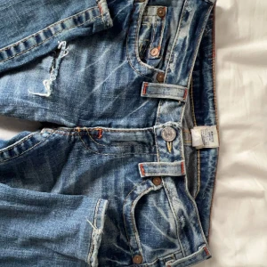 Lågmidjade True religion jeans  - STRAIGHT LEG! Säljer true religion jeans med hål som inte har några direkta defekter förutom ett insytt snöre för att göra de mindre i midjan (se bild 3)❤️De är köpta i Danmark för 1000 och använda fåtal gånger. Kontakta för bilder och frågor🩷🩷