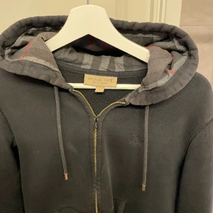 Burberry zip hoodie  - Burberry zip hoodie storlek S. Väldigt använd och har några hål och slitningar därav priset! Kom Pm om du vill ha bild på hål/ slitningar