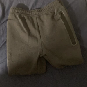 Mörk gråa nike tech byxor - Mörk gråa nike tech byxor med guldigt nike märke. Säljer dem eftersom att jag köpte dem i fel storlek, aldrig använda. Skick 10/10