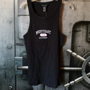 Linne  - Svart linne i ribbat tyg med broderat tryck. Nytt/oanvänt med lapp kvar! Storlek 36, men jag skulle säga att det är något litet i storlek. 