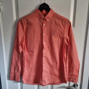 Fet orange/rosa Gant skjorta inför sommaren! Den är sparsamt använd och i fint skick. Den passar dig som är 13-14 år. 