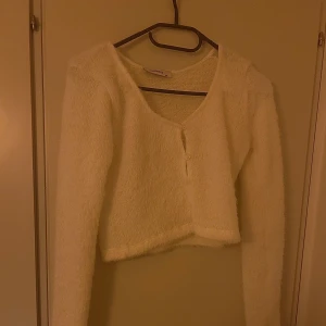 Vit stickad kort kofta  - En vit stickad kofta som är kort och i väldigt mjukt material. Har används fåtal gånger och är i mycket bra skick.