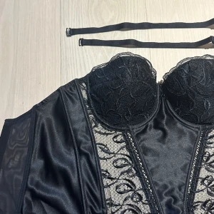 Svart korsett med bysthållare - En svart korsett med inbyggd bh storlek 80C, i spets och satin. Från märket lepel intimas. Medföljer original axelband samt stropparna som fäster för knästrumpor.   Mycket fint skick!  Hör av dig för fler bilder! 💐Obs katt finns i hemmet! 
