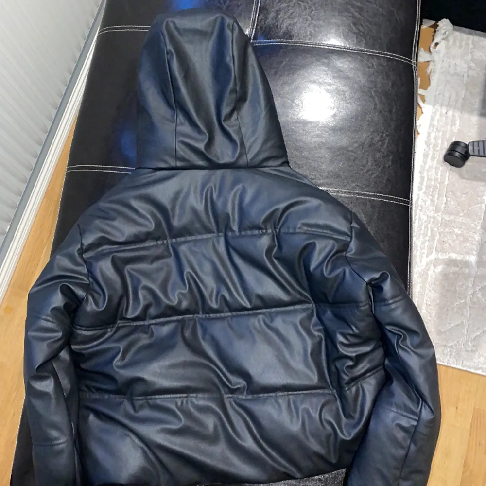 En svart skinn aktig dunjacka. Köpt från Zara, org pris:900 kr. Den är kort, har luva och fickor för förvaring. Storlek S. Använd fåtal gånger, ser ut som ny.. Jackor.