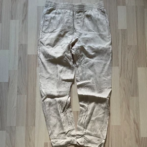 H&M linne byxor - 99kr - Beiga H&M ”regular fit” linnebyxor i storlek medium. Yttertyg 100% lin, fickorna 91% polyester & 9% bomull. Fram fickor & en oöppbar höger bakficka, spännbara snören vid midjan. För mått/fler bilder skriv privat.