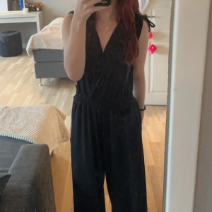 Byxdress - Pernilla Wahlgren - Säljer en elegant svart lång byxdress från Pernilla Wahlgren. Byxdressen är ärmlös med en djup v-ringning och har en smockad/resår midja som ger en fin passform. Perfekt för fest eller andra speciella tillfällen. Byxdressen är i nyskick och endast använd vid ett tillfälle!