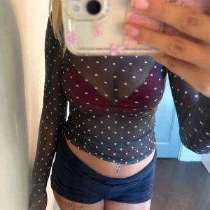 Svart mesh topp med vita prickar - Säljer en snygg svart mesh topp med vita prickar. Toppen är genomskinlig och har långa ärmar. Perfekt för fest eller en utekväll! Den är tight och croppad, vilket gör den supertrendig och stilren. Passar perfekt över en snygg bh eller bralette.