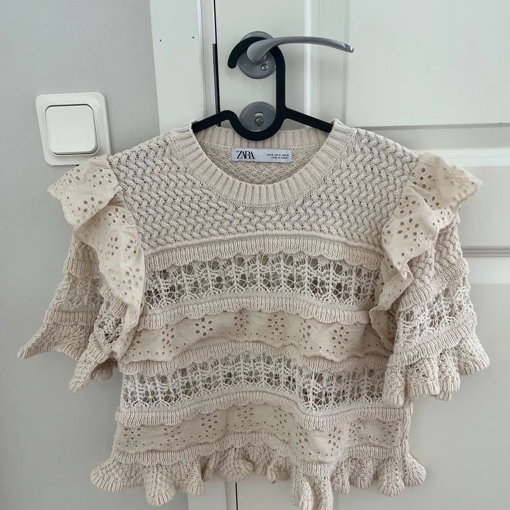 Säljer en söt beige stickad topp från Zara. Superfint spetsmönster och volanger, den har använts någon enstaka gång😊 Skriv om du har funderingar eller något annat💕. Tröjor & Koftor.