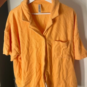 Orange frotté skjorta T-shirt  - Orange T-shirtskjorta i frotté, använd endast en gång så nyskick!! Storlek M från Lindex 