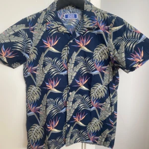 Hawai skjorta Jack & Jones - Tja! Säljer denna snygga Hawai skjorta från Jack & Jones perfekt att ha på sig utomlands. Den är i storlek 152 och i skick 10/10. Priset är 99 Kr. Skriv gärna om ni har några frågor eller funderingar.