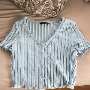 Somrig croppad topp  - Använd endast en gång längesedan. Skönt material, ljusblå. Knappar att lossa av 