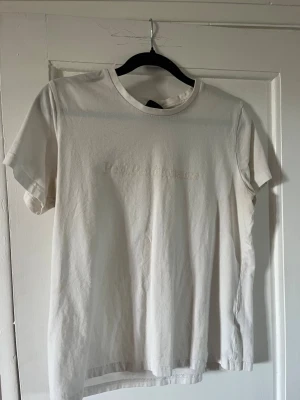 Vit t-shirt från Peak Performance - Säljer en stilren vit t-shirt från Peak Performance med diskret broderad logga på bröstet. Klassisk passform, rund hals och korta ärmar. Perfekt till jeans eller shorts för en clean look.